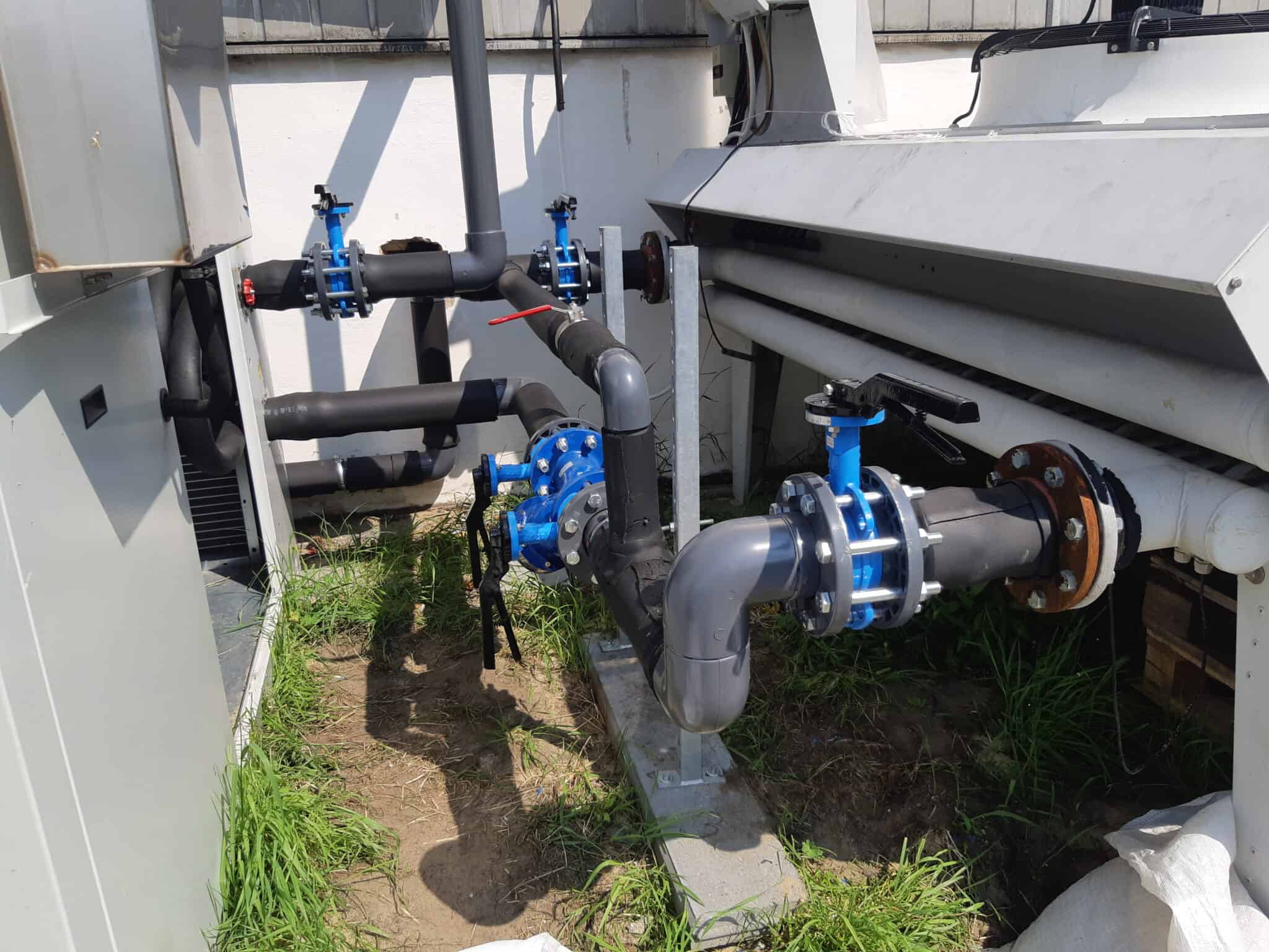 Rurociągi i zawory instalacji przemysłowej na zewnątrz, elementy systemu wodno-pompowego, fragment urządzeń technicznych na sprzyjającym świetle.