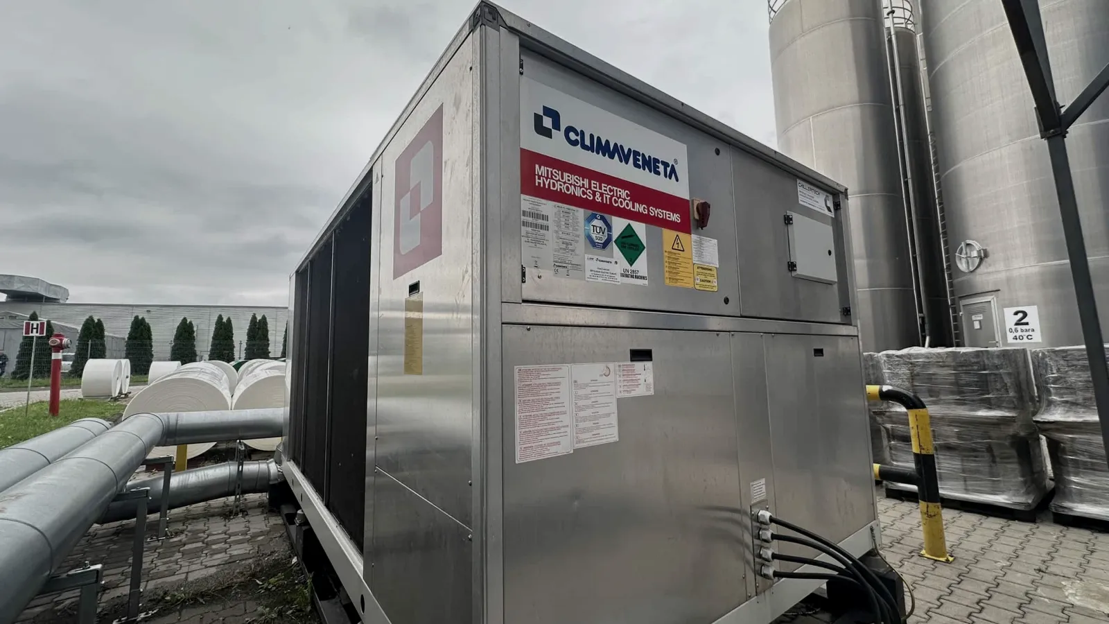 Przemysłowy klimatyzator na instalacji chłodniczej, z logo ClimaVento, z elementami montażowymi i rurami przyłączeń.
