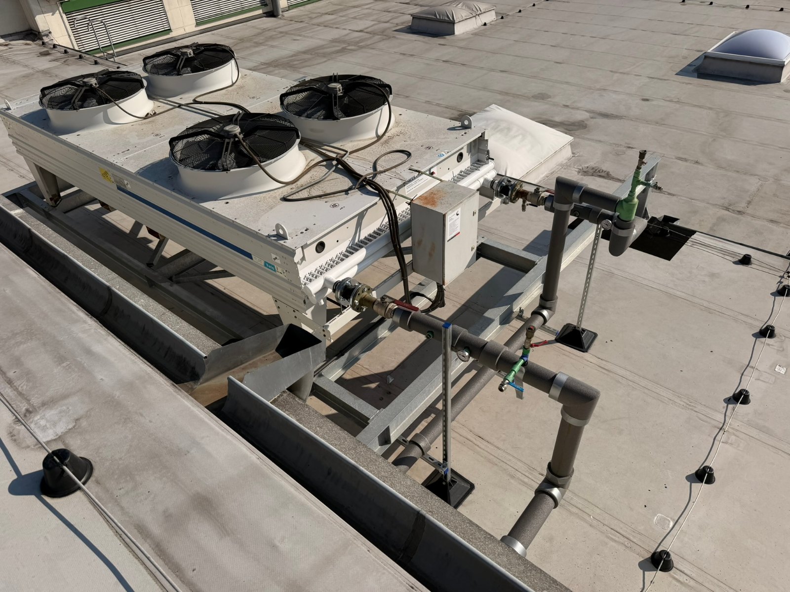 Dry cooler z czterema wentylatorami i rurociągi instalacji glikolowej na dachu zakładu